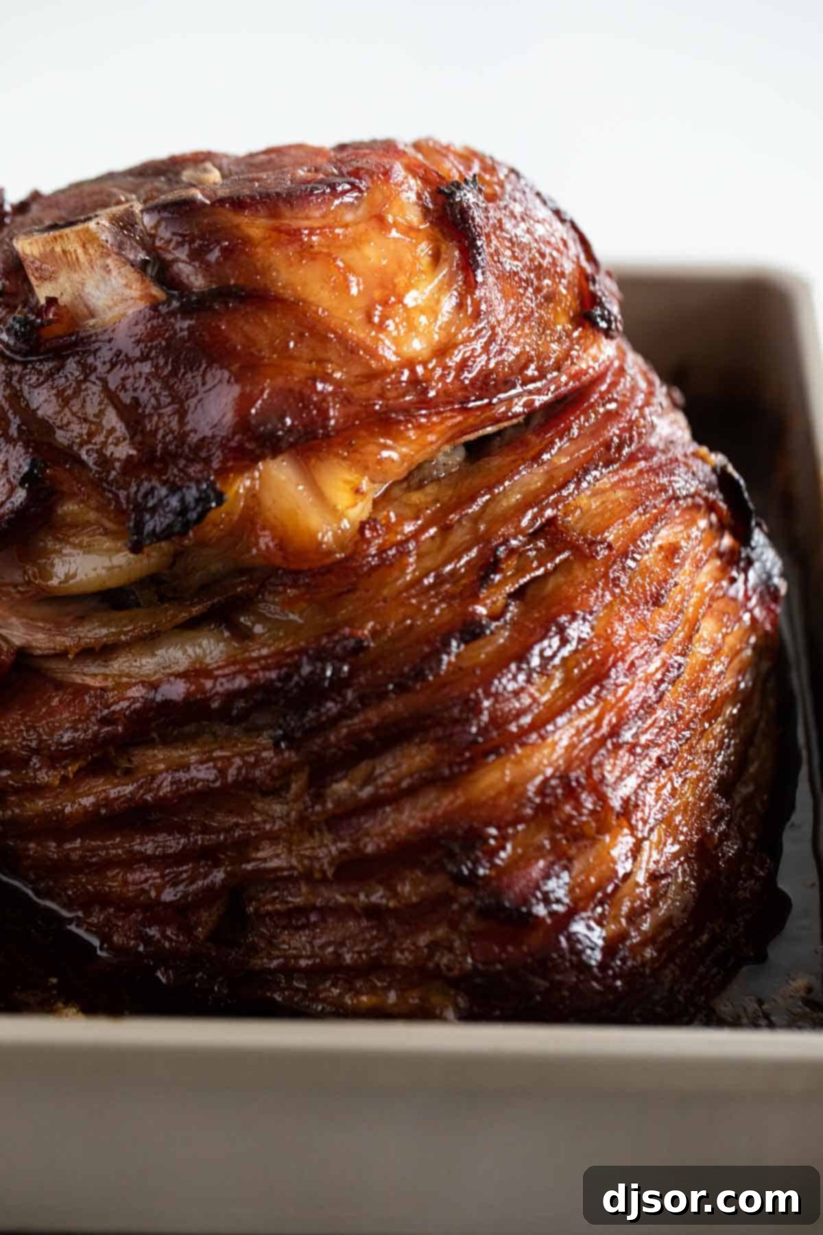 A full honey glazed ham, gleaming with caramelized glaze, resting in a large roasting pan after being perfectly baked.