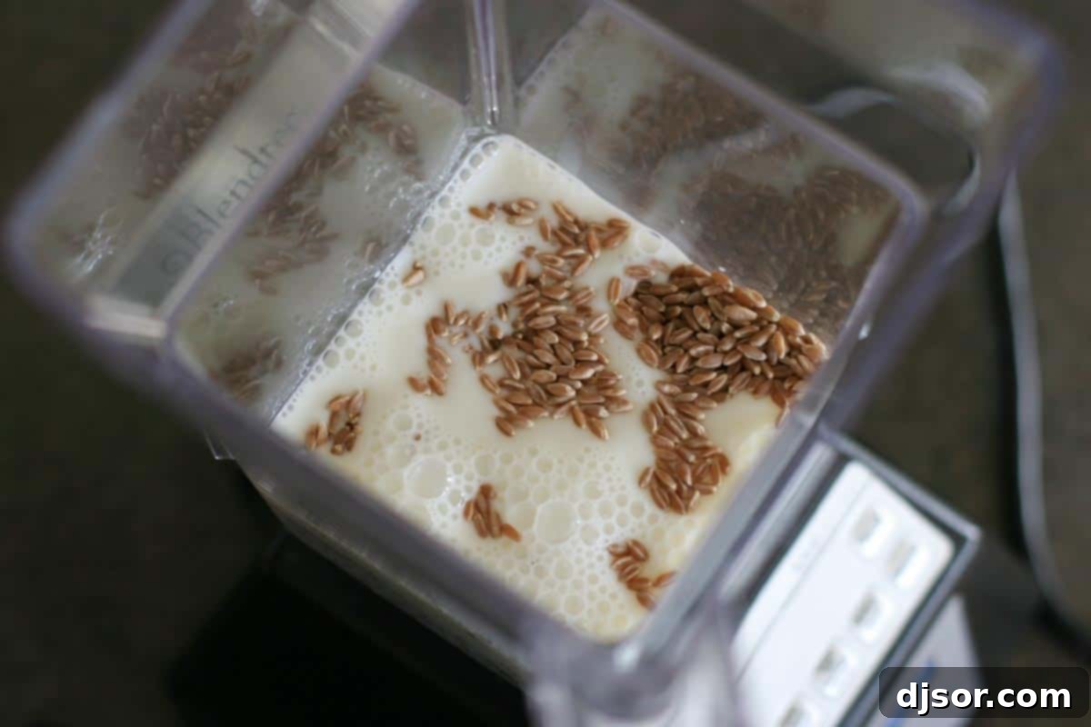 Whole Wheat Blender Pancakes - Use your blender to turn raw whole wheat into pancakes – the perfect breakfast! An overhead view inside a high-powered blender, showcasing the smooth, pale pancake batter with flecks of ground whole wheat.