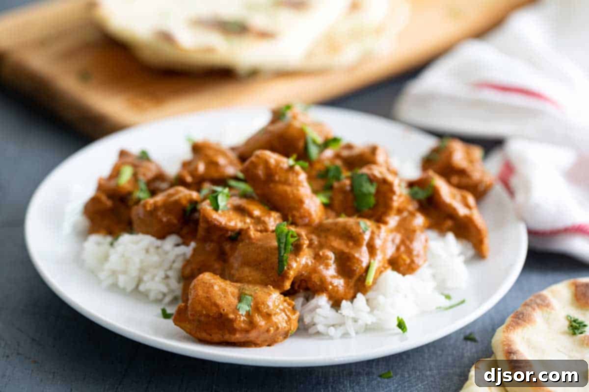 Butter Chicken over rice on a plate, garnished with fresh cilantro