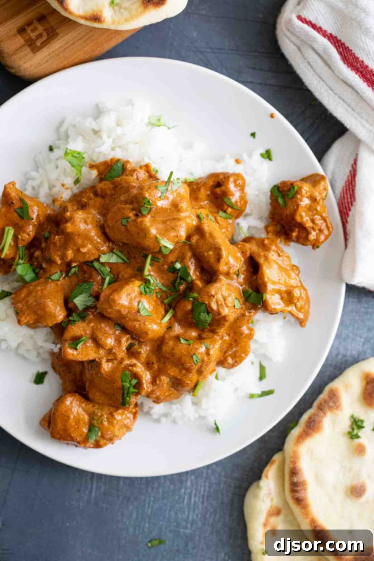Overhead view of Butter Chicken served over rice with a side of naan bread