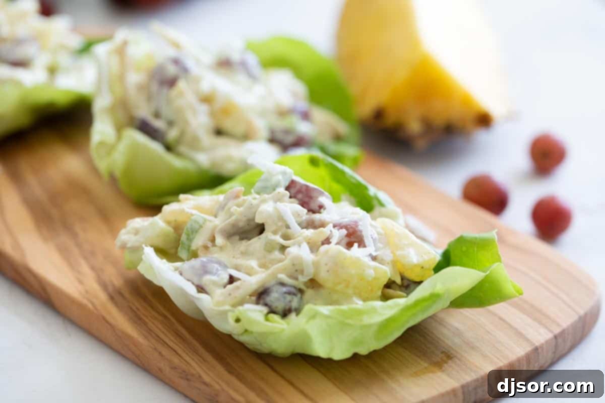 Chicken salad with an island twist - these Tropical Chicken Lettuce Wraps are filled with chicken, pineapple, grapes, and coconut with a creamy sauce to make the perfect lettuce wraps. chicken lettuce wraps with pineapple, grapes and coconut on a cutting board