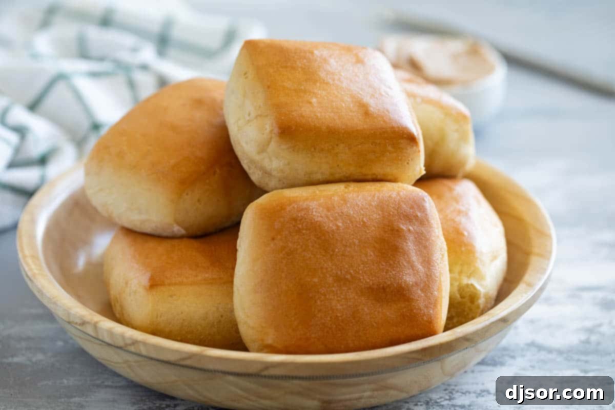 A bowl overflowing with freshly baked, golden brown Texas Roadhouse Rolls, exuding warmth and inviting aroma.