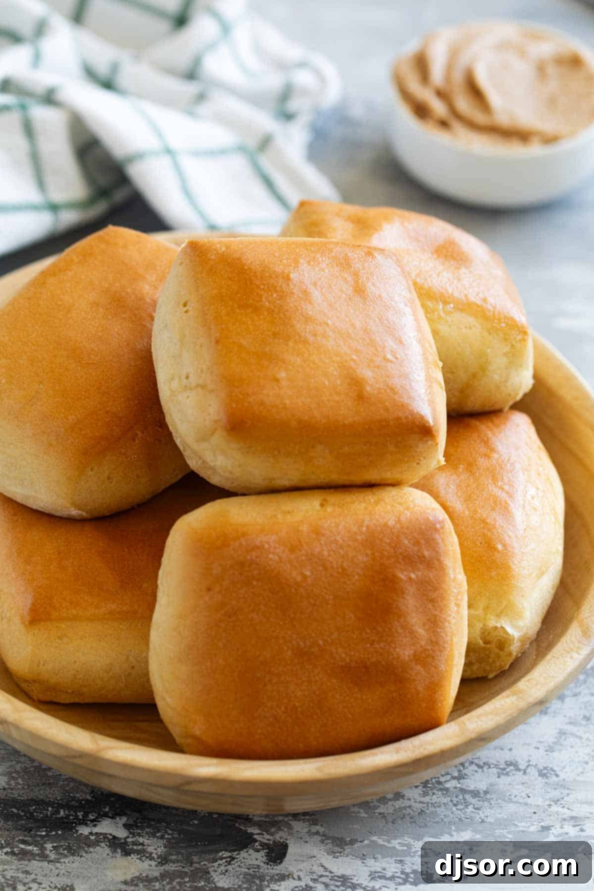 A rustic wooden bowl filled with a generous stack of perfectly baked, fluffy Texas Roadhouse Rolls, inviting you to enjoy.