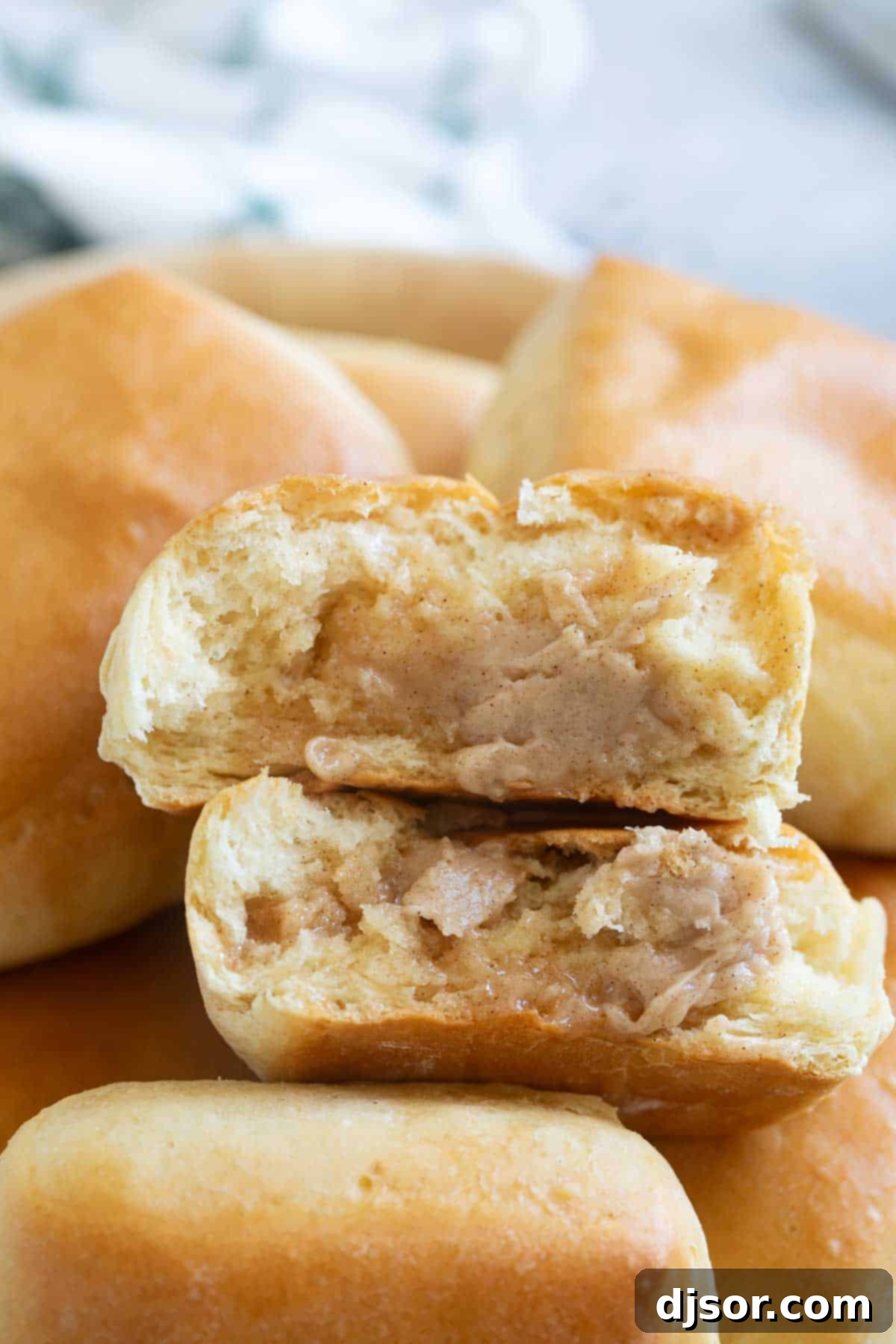 A warm Texas Roadhouse Roll, artfully split open and generously slathered with creamy cinnamon honey butter, revealing its invitingly fluffy interior.
