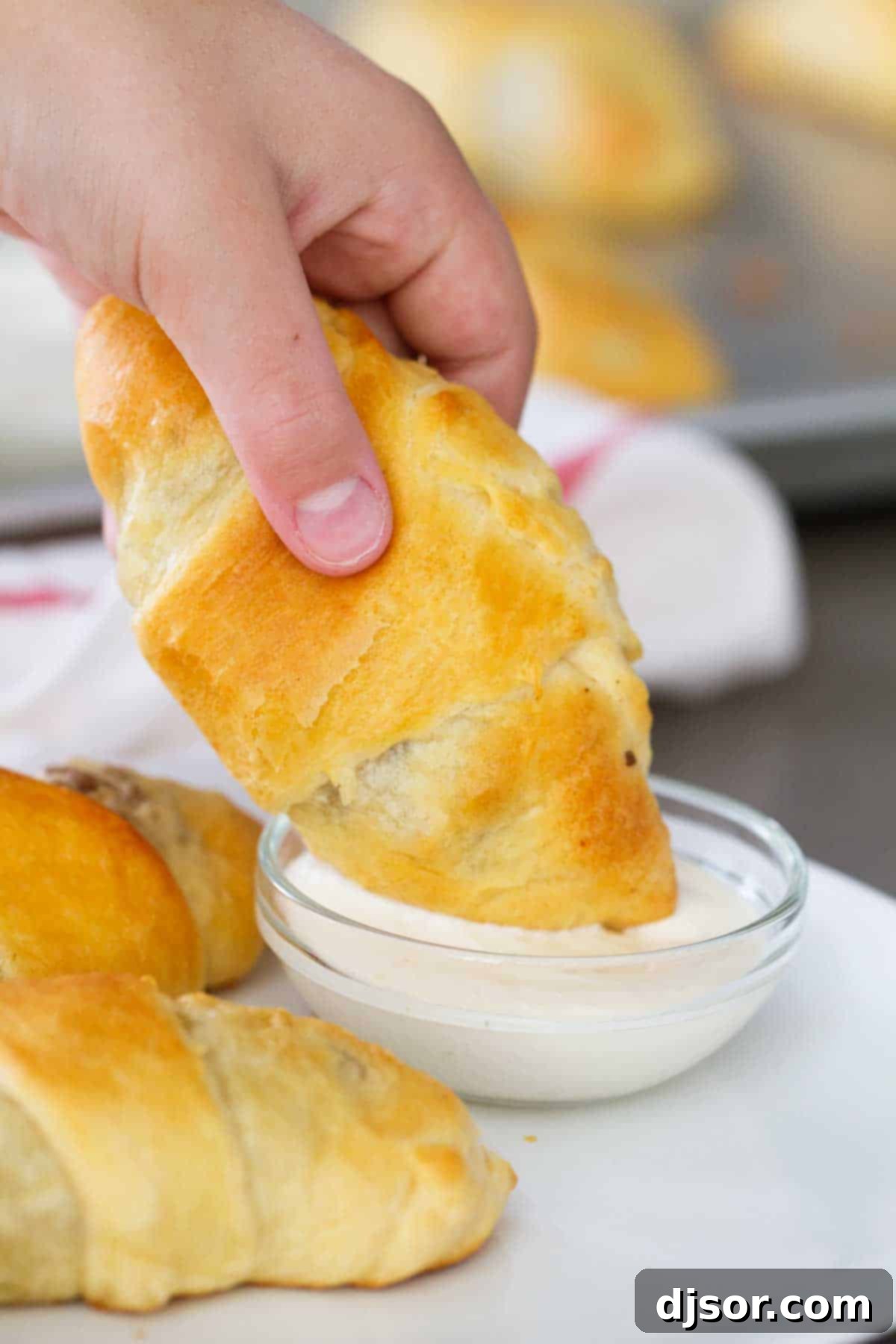 Savory Beef and Cabbage Rolls 6 Hand dipping a Cabbage and Beef Bundle into a bowl of creamy horseradish mayo.