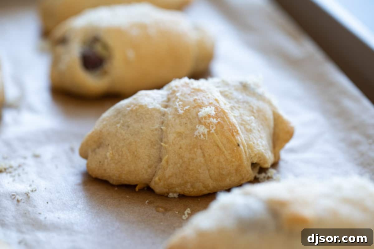 Chicken, cream cheese, and mushrooms are rolled and baked inside crescent rolls for these easy, family favorite Chicken Crescent Rolls. Finished chicken crescent rolls on a baking sheet.
