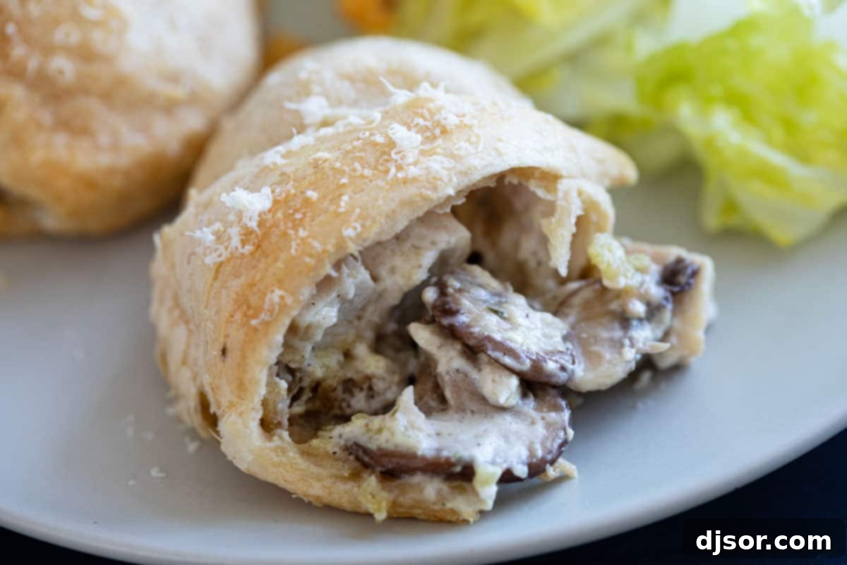 Chicken, cream cheese, and mushrooms are rolled and baked inside crescent rolls for these easy, family favorite Chicken Crescent Rolls. Chicken crescent roll showing the inside with chicken and mushrooms.