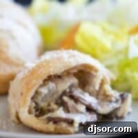 Savory Chicken Pastry Swirls 2 Chicken crescent roll on a plate with a bite taken from it showing the inside.