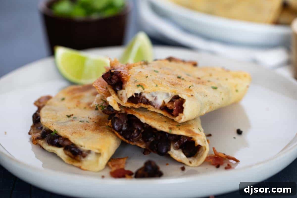 three Black Bean Tacos on a plate with a bite taken from one