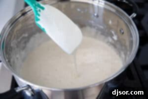Marshmallow mixture being made in a saucepan for fruity pebble rice crispy treats.