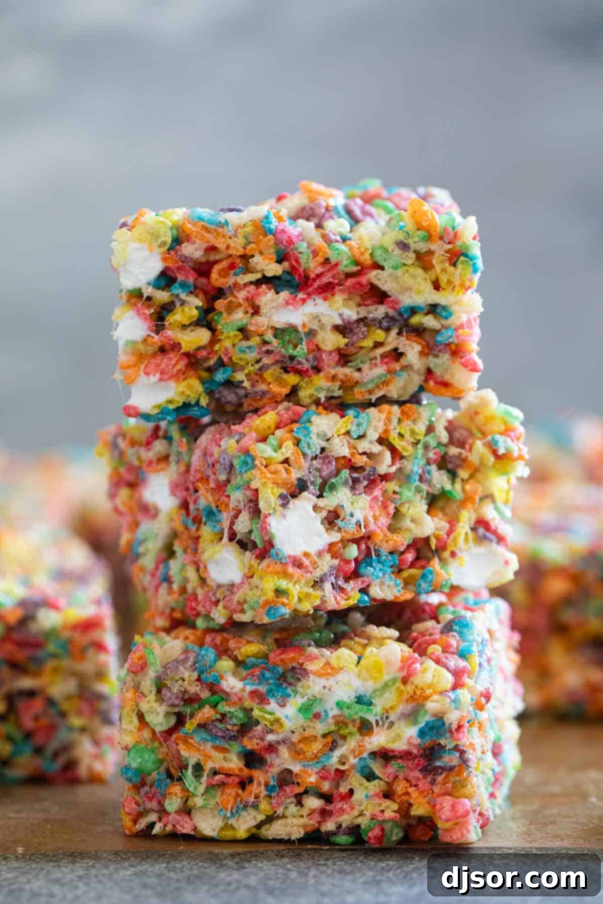 Several Fruity Pebble Rice Crispy Treats stacked neatly on top of each other, highlighting their vibrant colors.