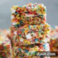 Fruity Pebble Rice Crispy Treats stacked on top of each other, showcasing vibrant colors.