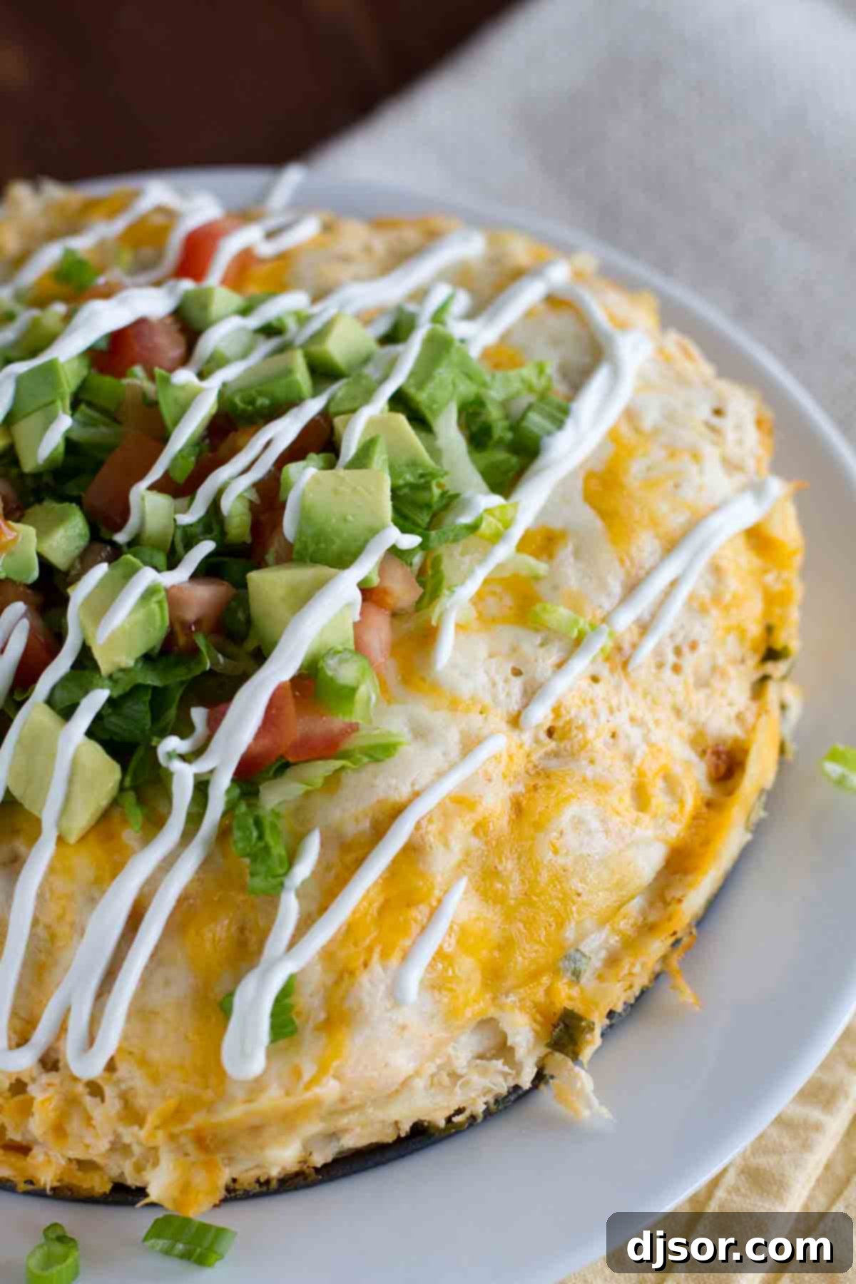 With layers of flavor, this easy to assemble Chicken Tortilla Stack is great for a weeknight meal, or even for company. A complete Chicken Tortilla Stack, generously drizzled with creamy sour cream and garnished, showcasing its golden-brown perfection.