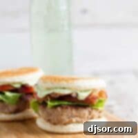 Two Club Burger Sliders with Avocado-Ranch Dressing on a cutting board with drink in the back