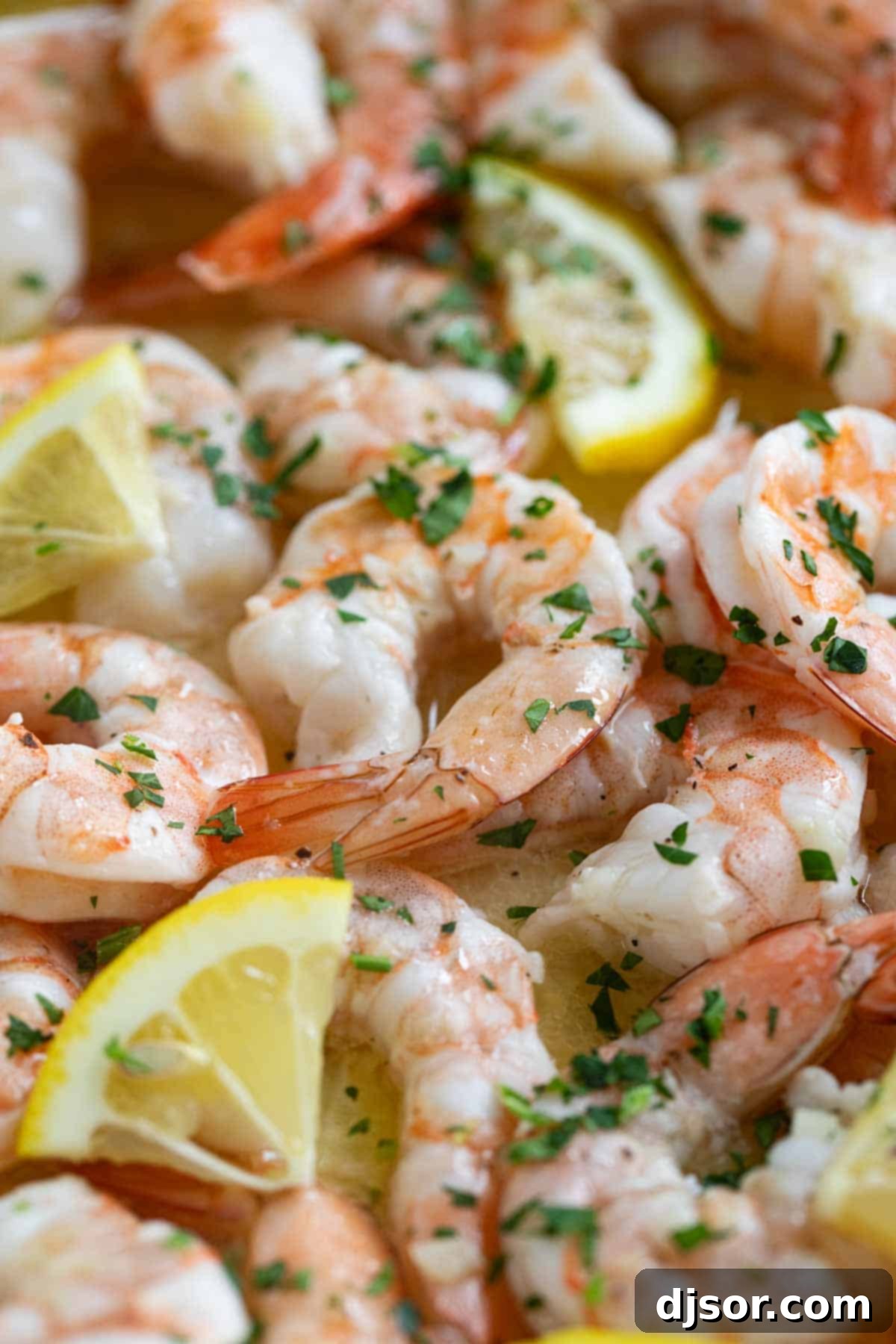 Lemon Garlic Baked Shrimp 6 Close-up of baked shrimp in a white baking dish, garnished with lemon slices and fresh parsley, showing its vibrant pink color.