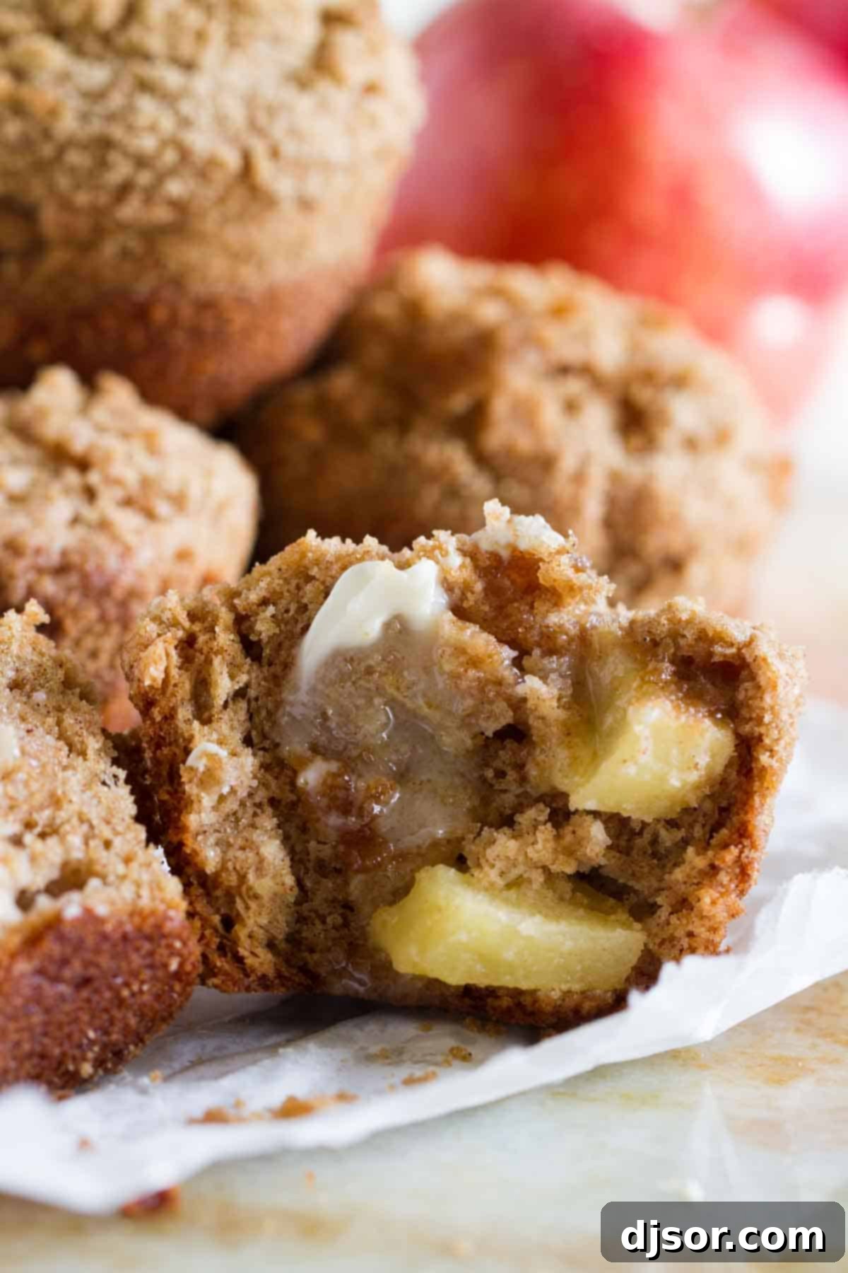 A close-up of an Apple Muffin, broken open to reveal generous chunks of fresh apple and a tender, cinnamon-spiced interior.