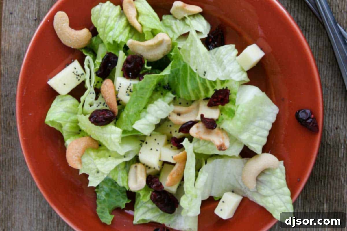 A vibrant Winter Salad featuring fresh pears, crisp apples, crunchy cashews, and a drizzle of homemade Lemon Poppy Seed Dressing.
