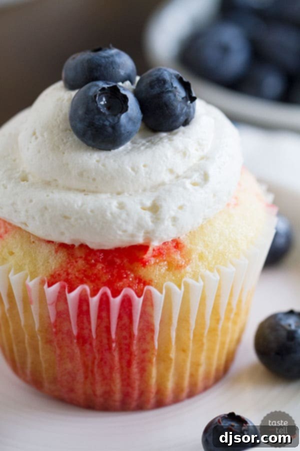 Jiggly Jell-O Poke Cupcakes 3 A close-up of a festive Jello poke cupcake, perfect for Fourth of July celebrations, with red gelatin seeping into the vanilla cake.