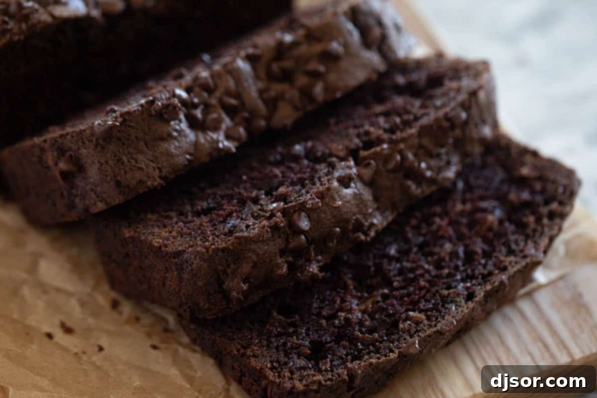 A beautifully sliced loaf of moist chocolate zucchini bread on a rustic cutting board, ready to be enjoyed.