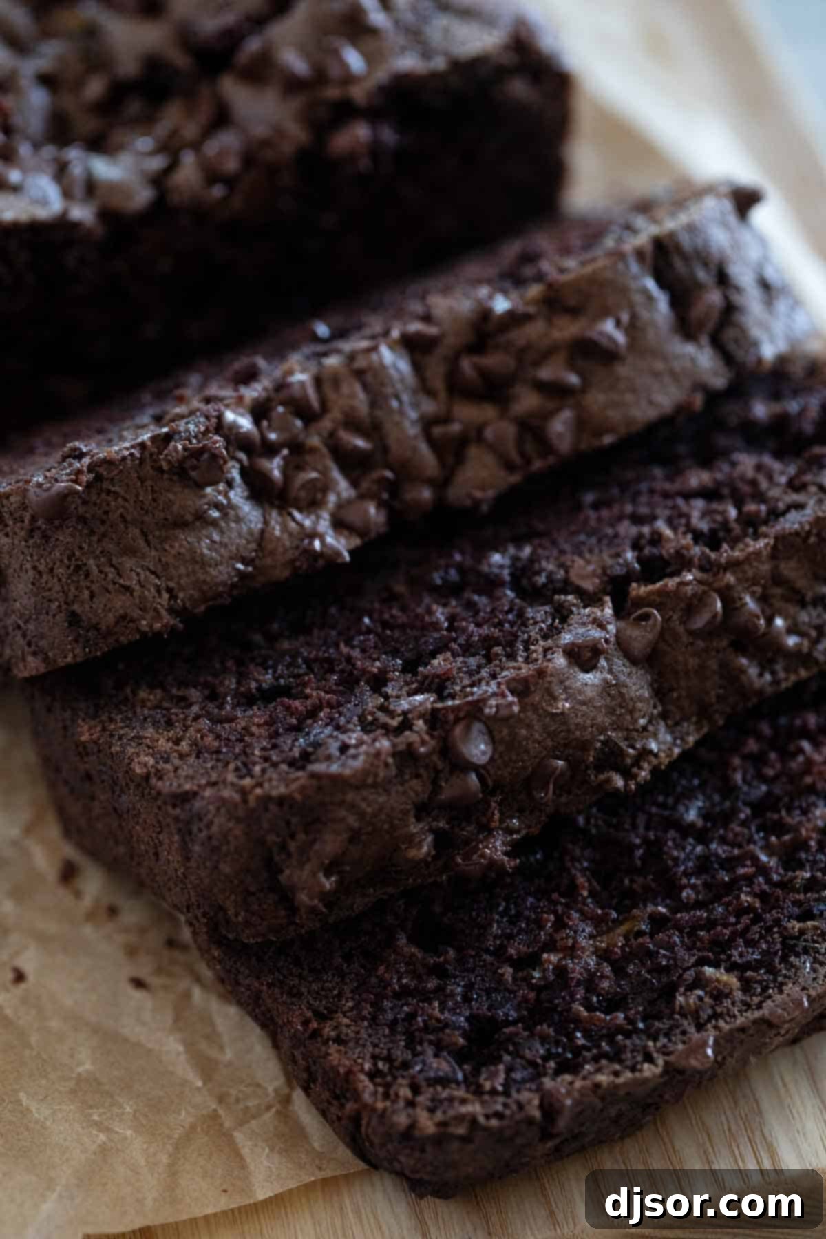 Close-up of freshly baked slices of chocolate zucchini bread, topped with mini chocolate chips.