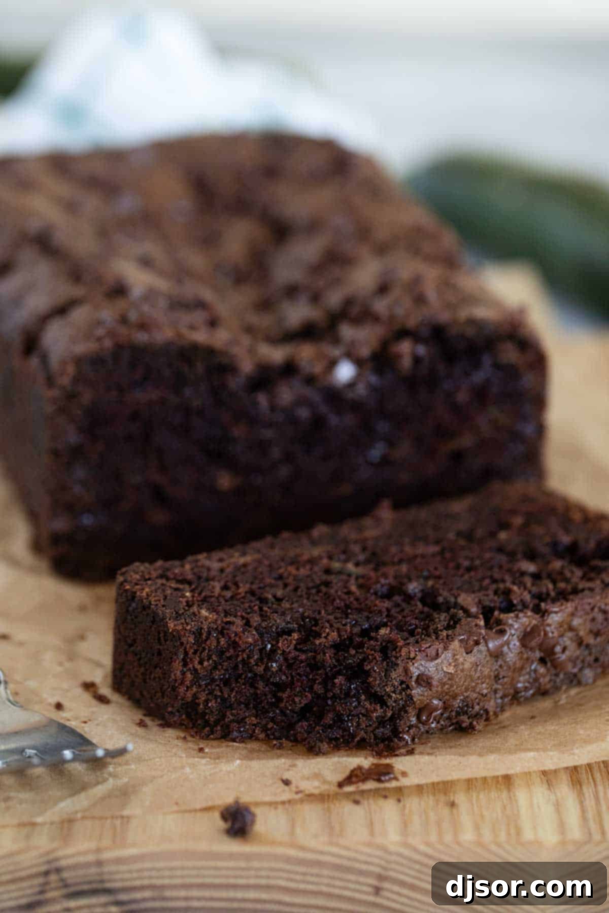 A close-up shot of a slice of chocolate zucchini bread, with a bite taken out, showing its moist interior.