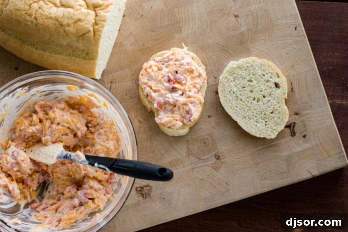 Preparing a pimento grilled cheese sandwich on French bread on a griddle.