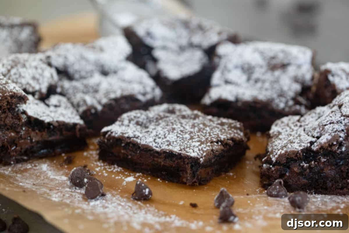Cake mix brownies sprinkled with powdered sugar on a piece of parchment paper, ready to be cut.