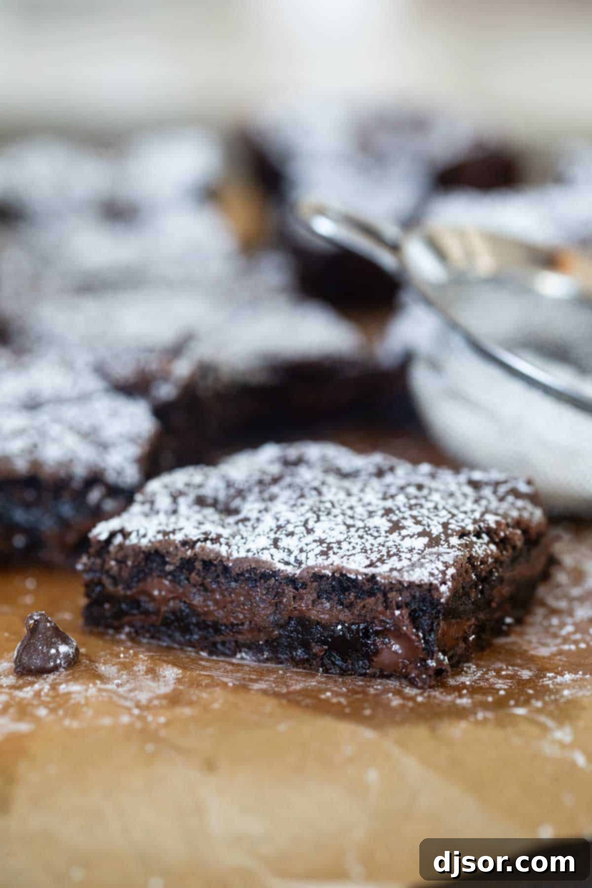 A single cake mix brownie topped with powdered sugar, sitting on a parchment paper.