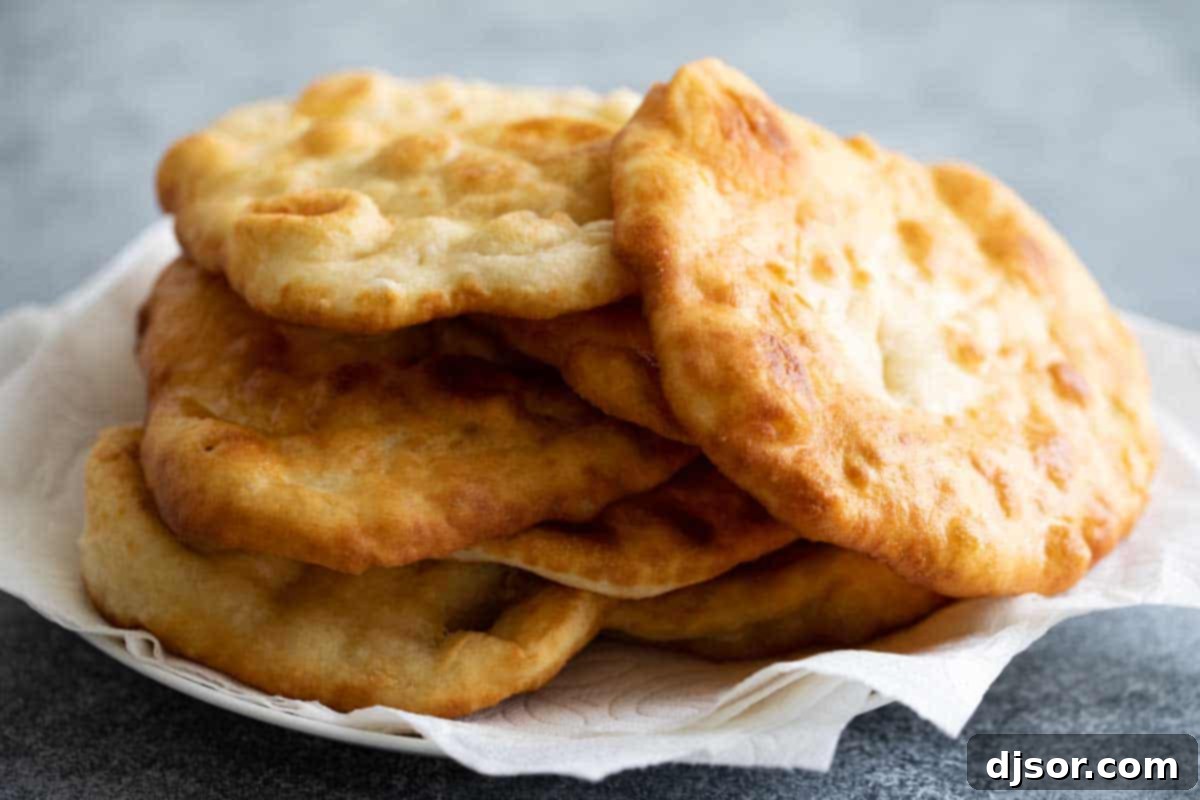 A tempting stack of warm, freshly fried bread, promising a delightful base for your Navajo Tacos or a sweet treat. A stack of freshly made, golden-brown fry bread, ready to be topped or enjoyed plain