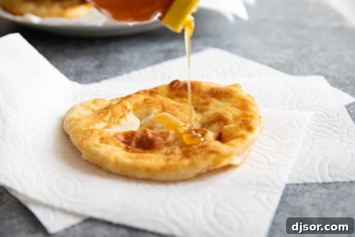 Leftover fry bread transforms into a delightful dessert, simply topped with sweet honey. Freshly made fry bread being topped with sweet honey for dessert