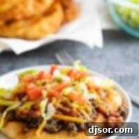 Fry Bread Tacos 2 Navajo taco topped with seasoned meat and beans, with additional fry bread in the background