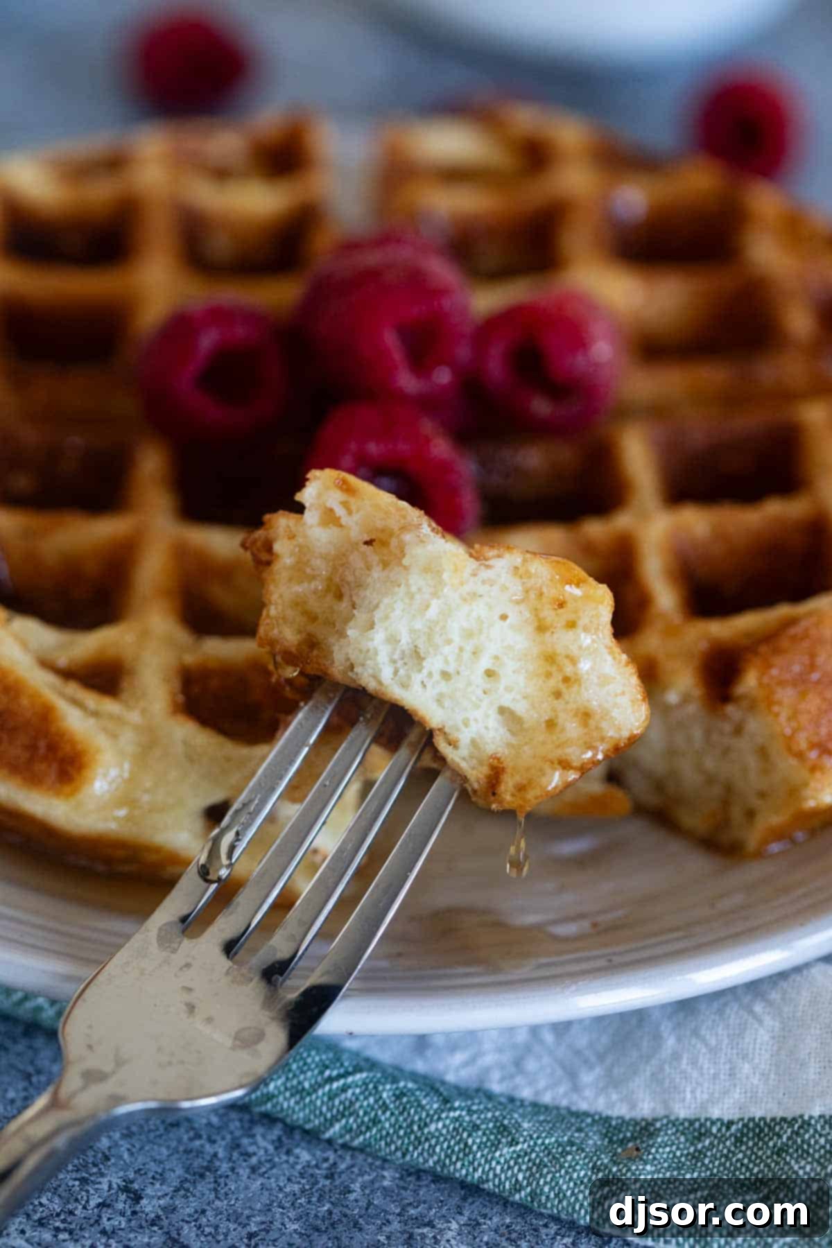 Classic Belgian Waffles 9 Bite of Belgian waffle on a fork with a drip of syrup coming off of it.