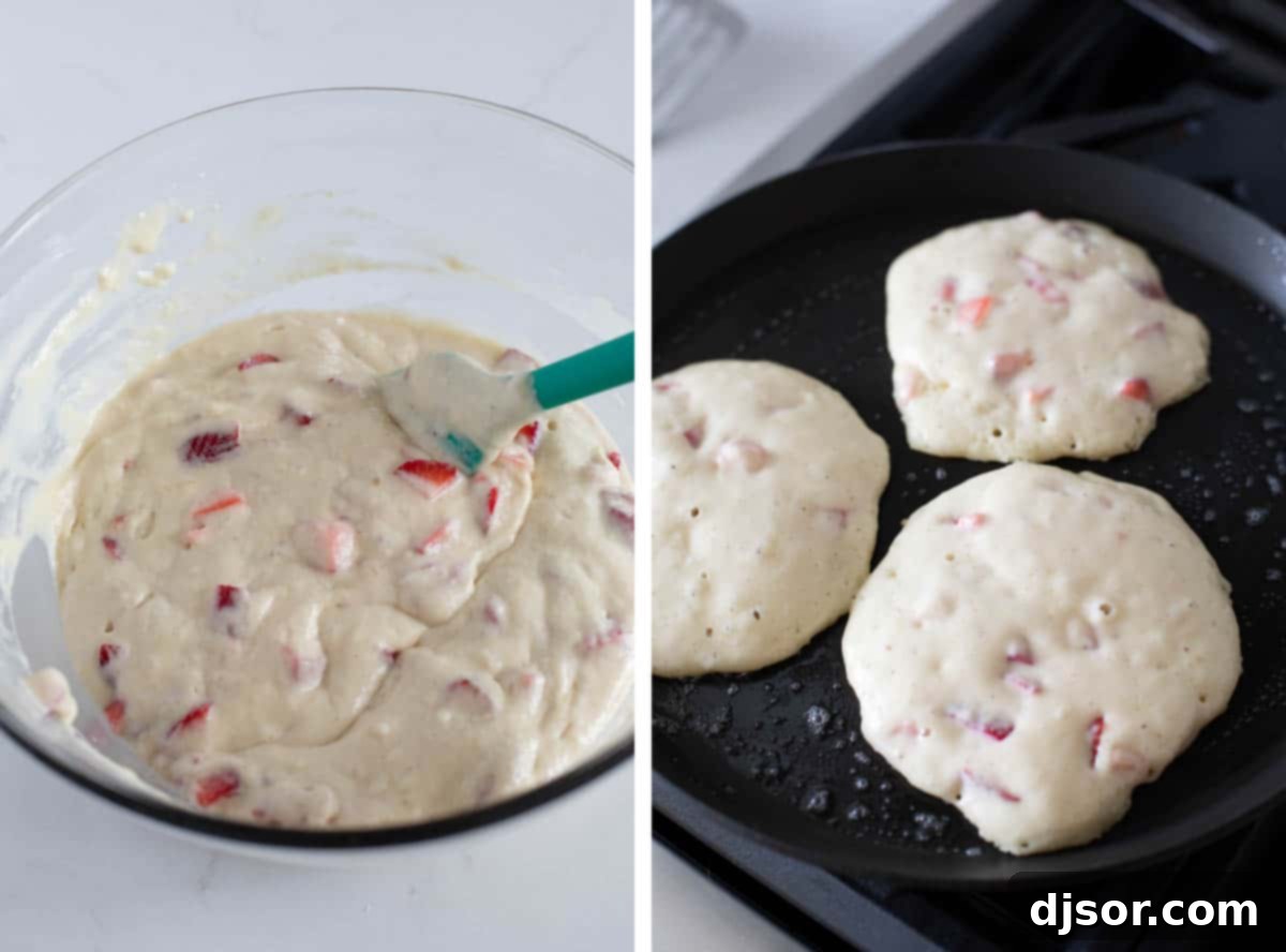 A large bowl of pancake batter, showing a thick consistency and streaks of flour, indicating it has just been mixed but not overmixed, preparing for strawberries.