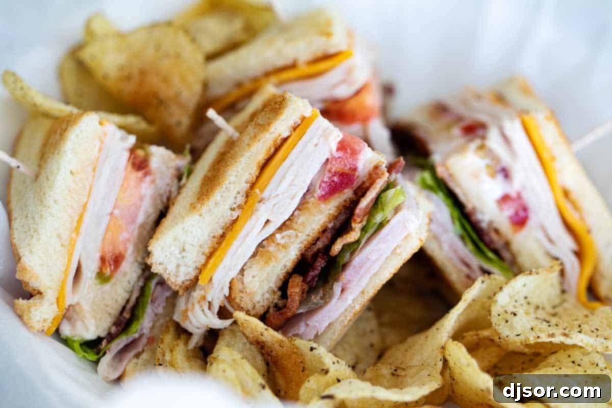 pieces of club sandwich in a basket with potato chips