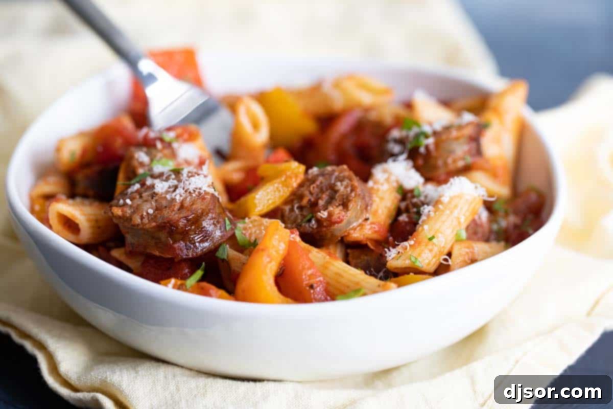 A comforting bowl of Sausage and Peppers Pasta, perfect for a flavorful dinner. white bowl of sausage and peppers pasta, garnished with fresh herbs