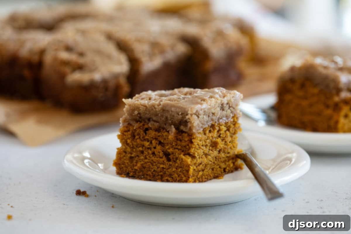Slice of pumpkin coffee cake on a plate, showcasing its moist texture, crumb topping, and glaze.