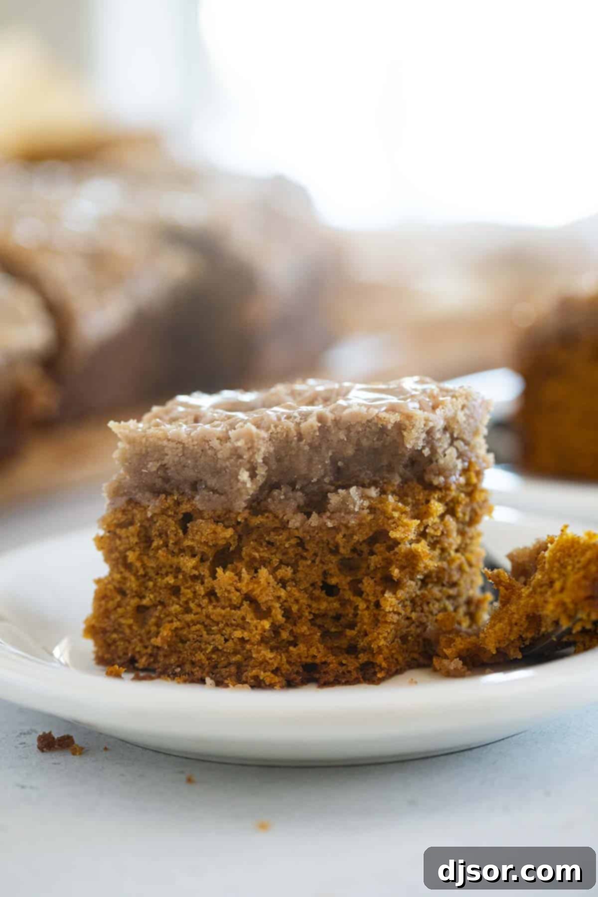 Slice of pumpkin coffee cake with a bite taken from it, showing the soft interior and crispy streusel.