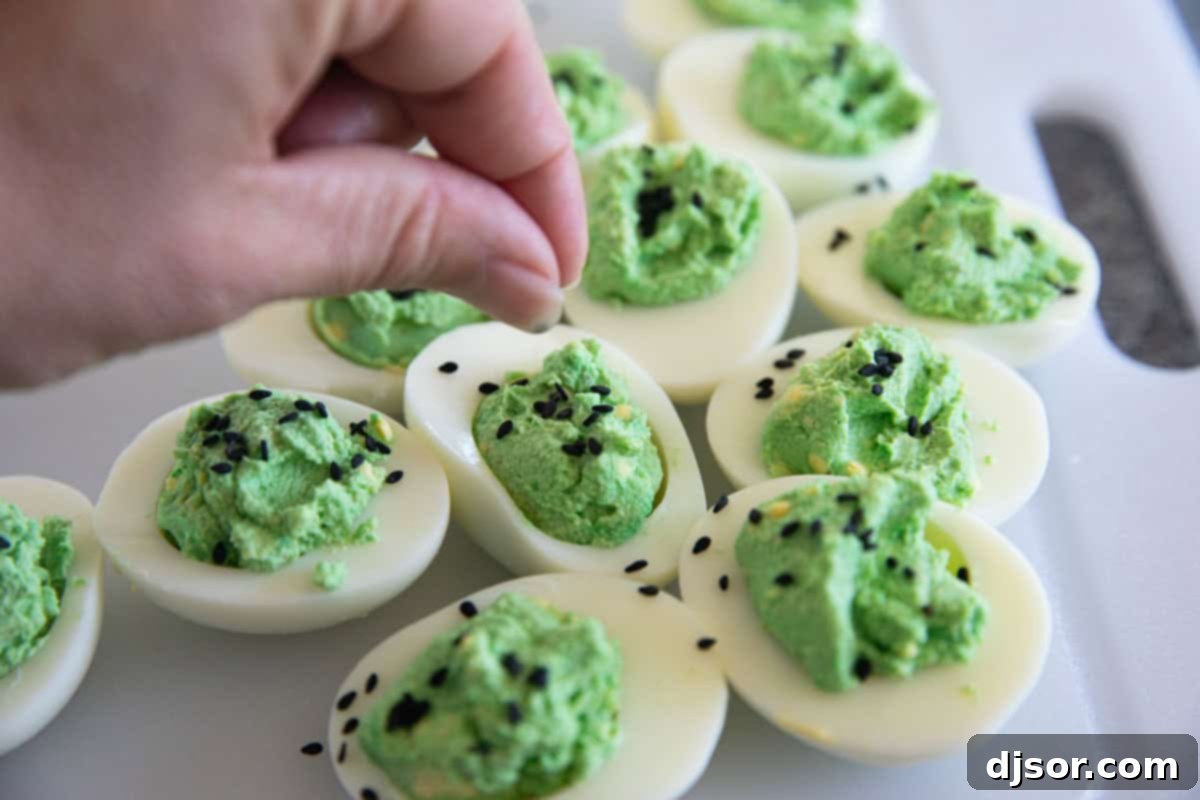 Ghastly Deviled Eggs 6 Green deviled eggs sprinkled with black sesame seeds for a Halloween-themed appetizer.