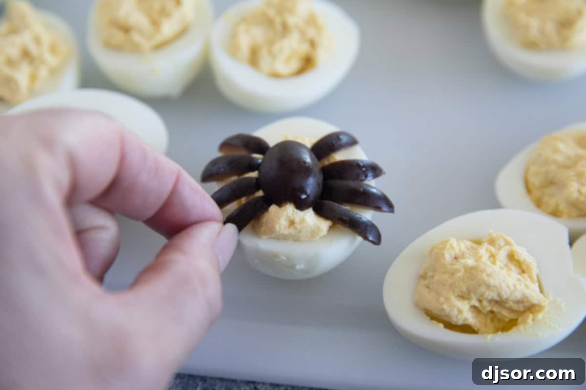 Ghastly Deviled Eggs 7 Close-up of a deviled egg decorated with a black olive spider, perfect for Halloween.