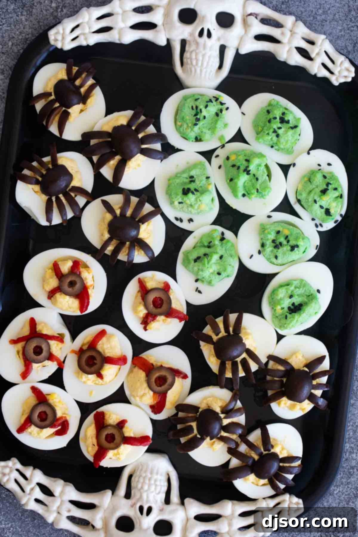 Ghastly Deviled Eggs 10 A vibrant display of Halloween deviled eggs, featuring green monster eggs, spider eggs, and bloodshot eyeball designs.