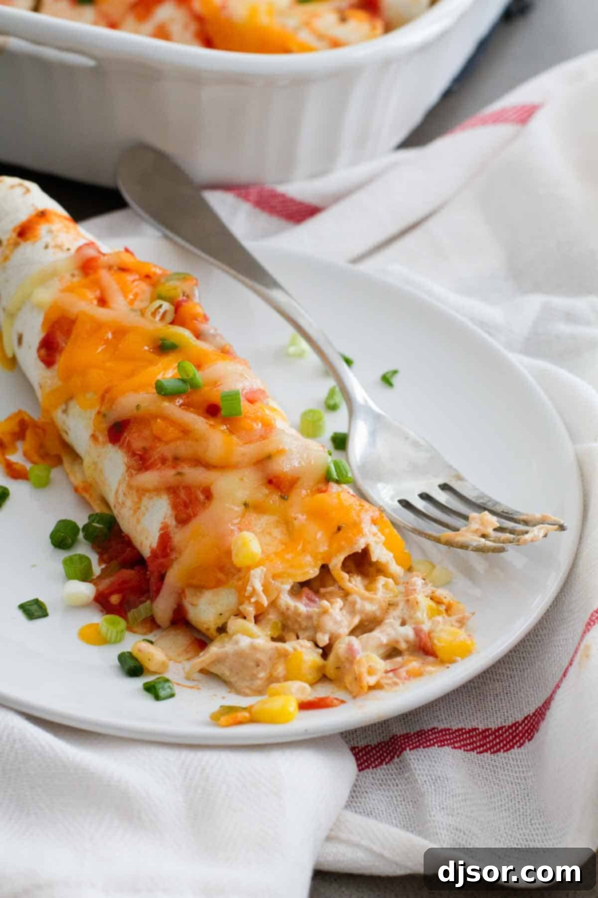 Creamy Chicken Enchilada Bake 5 A close-up shot of a Cream Cheese Chicken Enchilada, cut open to reveal the creamy chicken and corn filling, with a bite taken.