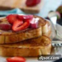 Pain Perdu 10 Slices of fluffy French Toast topped with sweet syrup and fresh berries, showcasing a perfect golden crust.