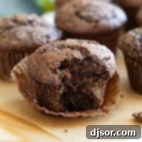 Velvet Chocolate Zucchini Muffins 2 Chocolate zucchini muffin unwrapped with a bite taken from it.