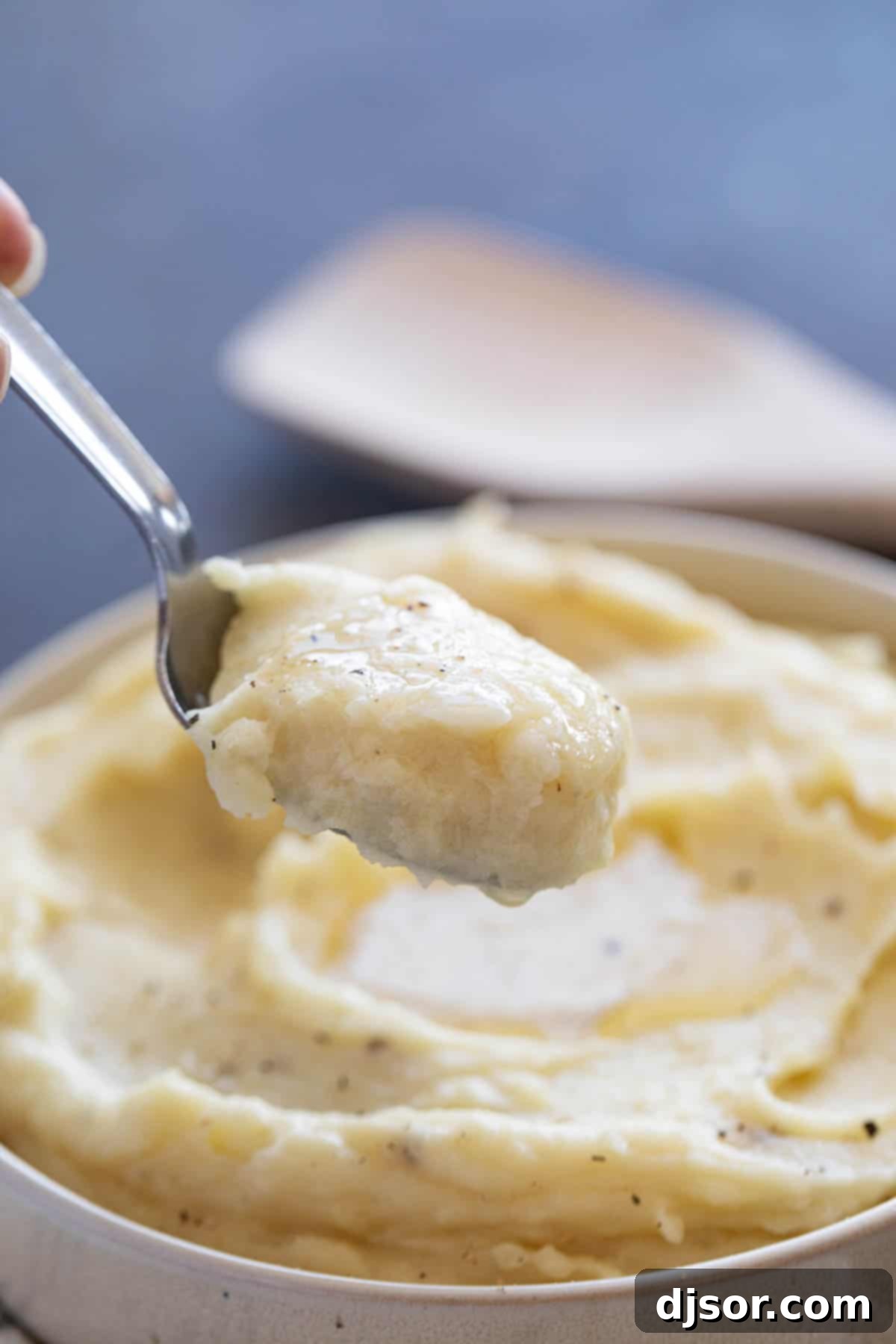 Perfectly Creamy Crockpot Mashed Potatoes 7 A spoon scooping a generous portion of creamy slow cooker mashed potatoes from the pot, showcasing its fluffy texture.