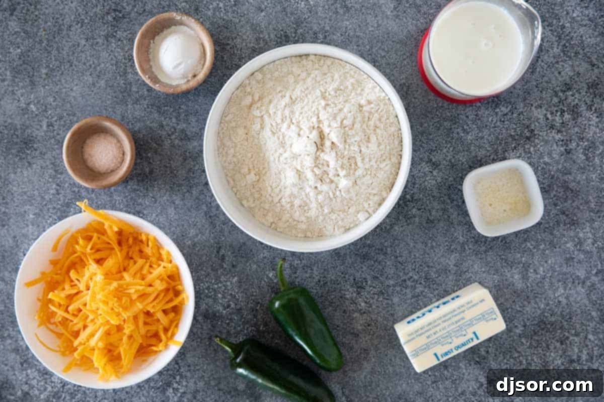 Arrangement of fresh ingredients for making Jalapeno Cheddar Biscuits, including flour, butter, buttermilk, cheddar cheese, and fresh jalapeños.