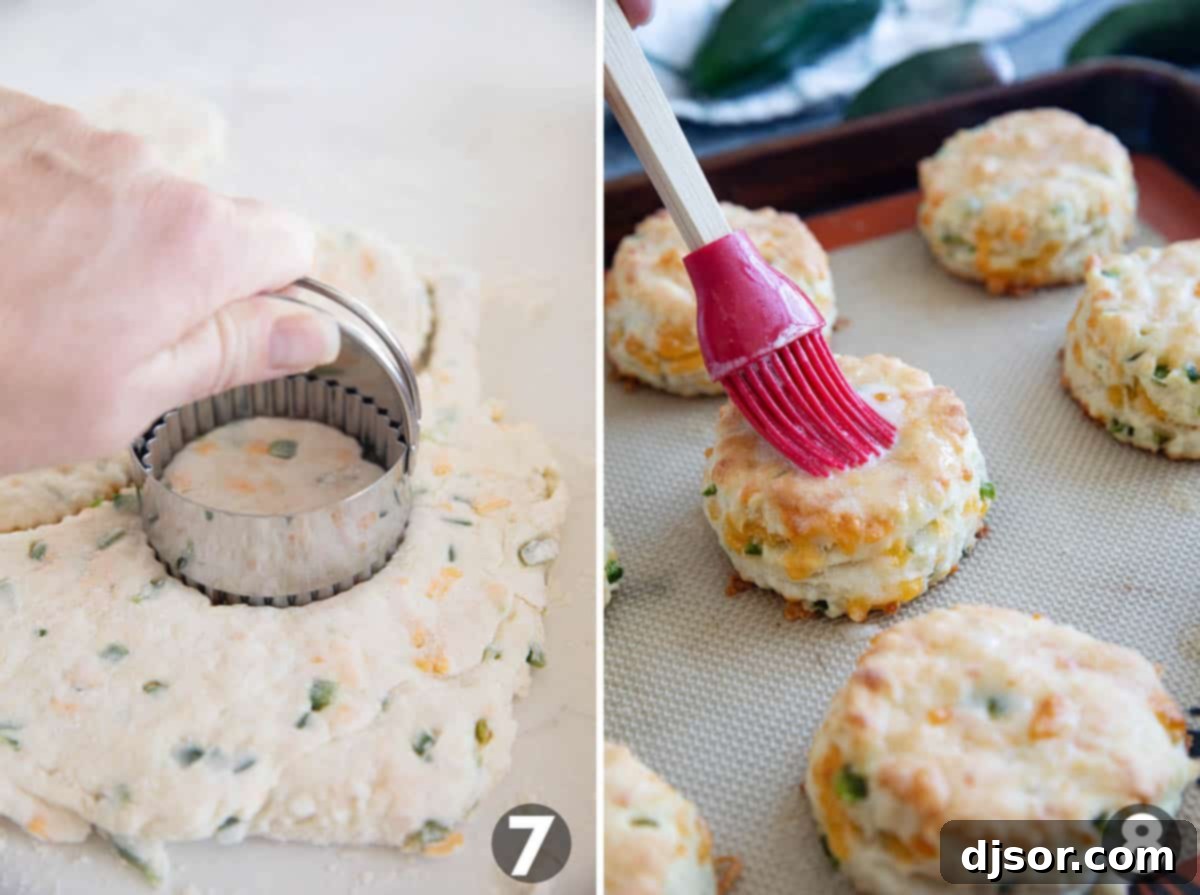 Cutting biscuit dough with a round cutter and brushing melted butter on top of freshly baked Jalapeno Cheddar Biscuits.