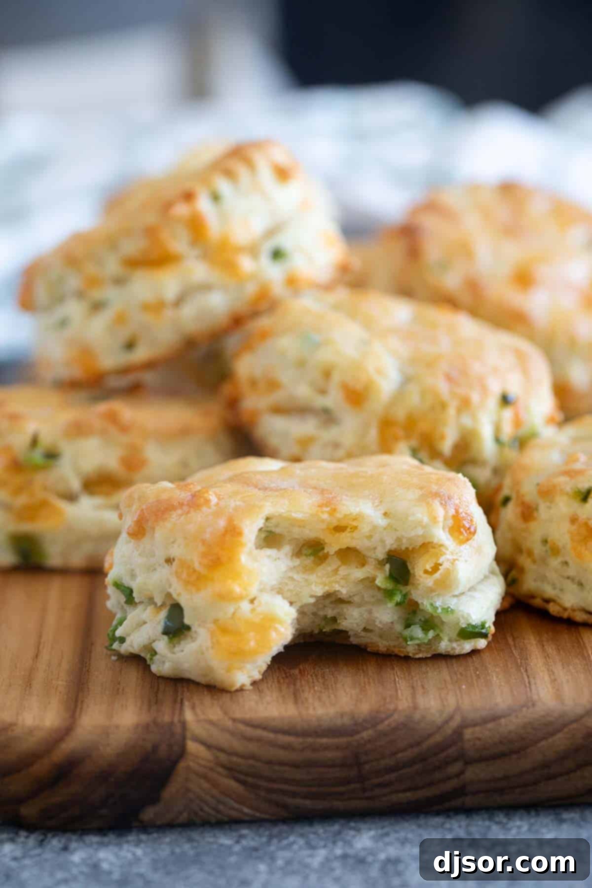 A close-up of a Jalapeno Cheddar Biscuit with a bite taken out, revealing its fluffy interior and cheese bits.