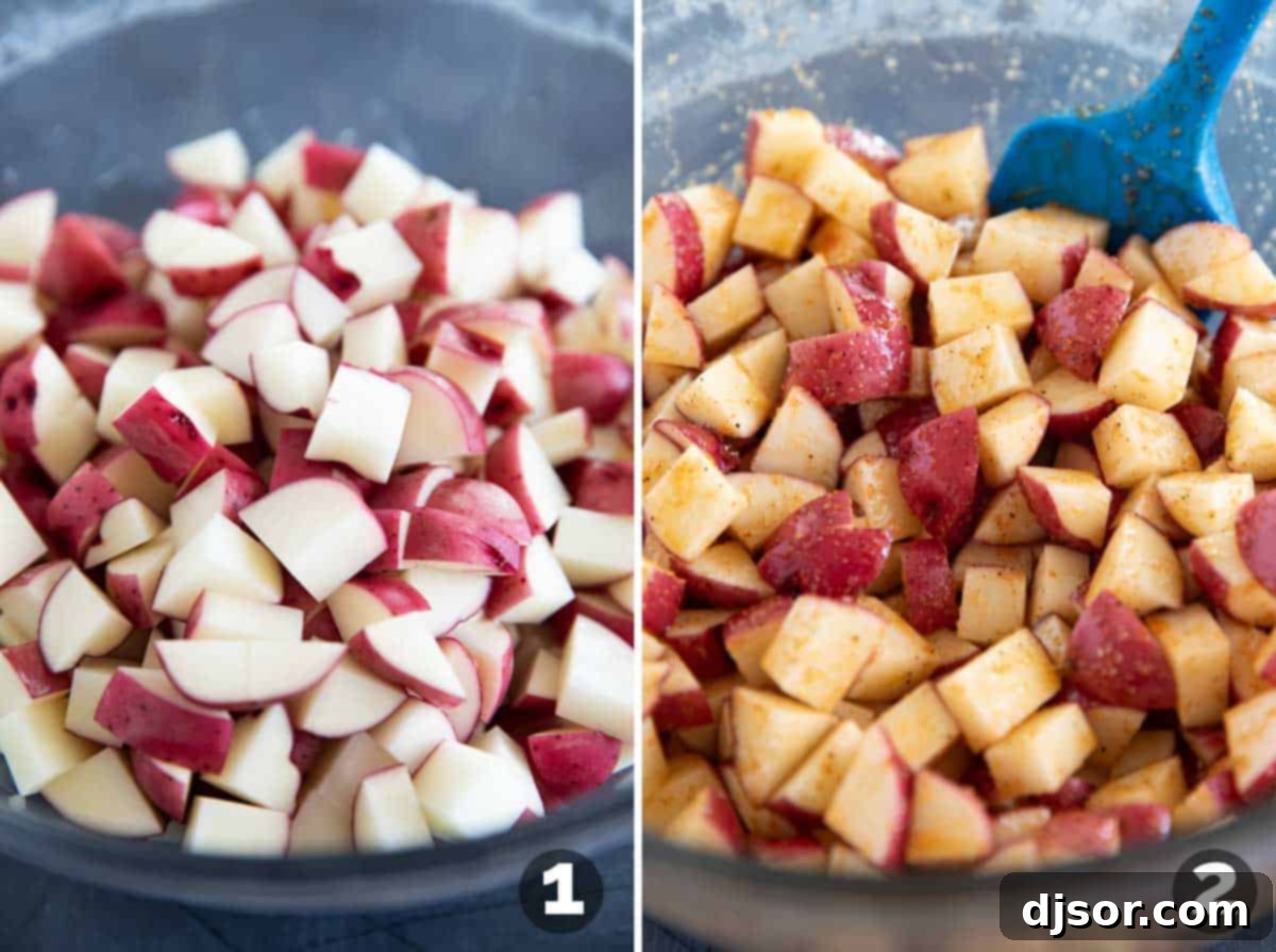 A close-up shot of diced raw potatoes being mixed in a large bowl with olive oil and a blend of spices, ensuring even coating before roasting.