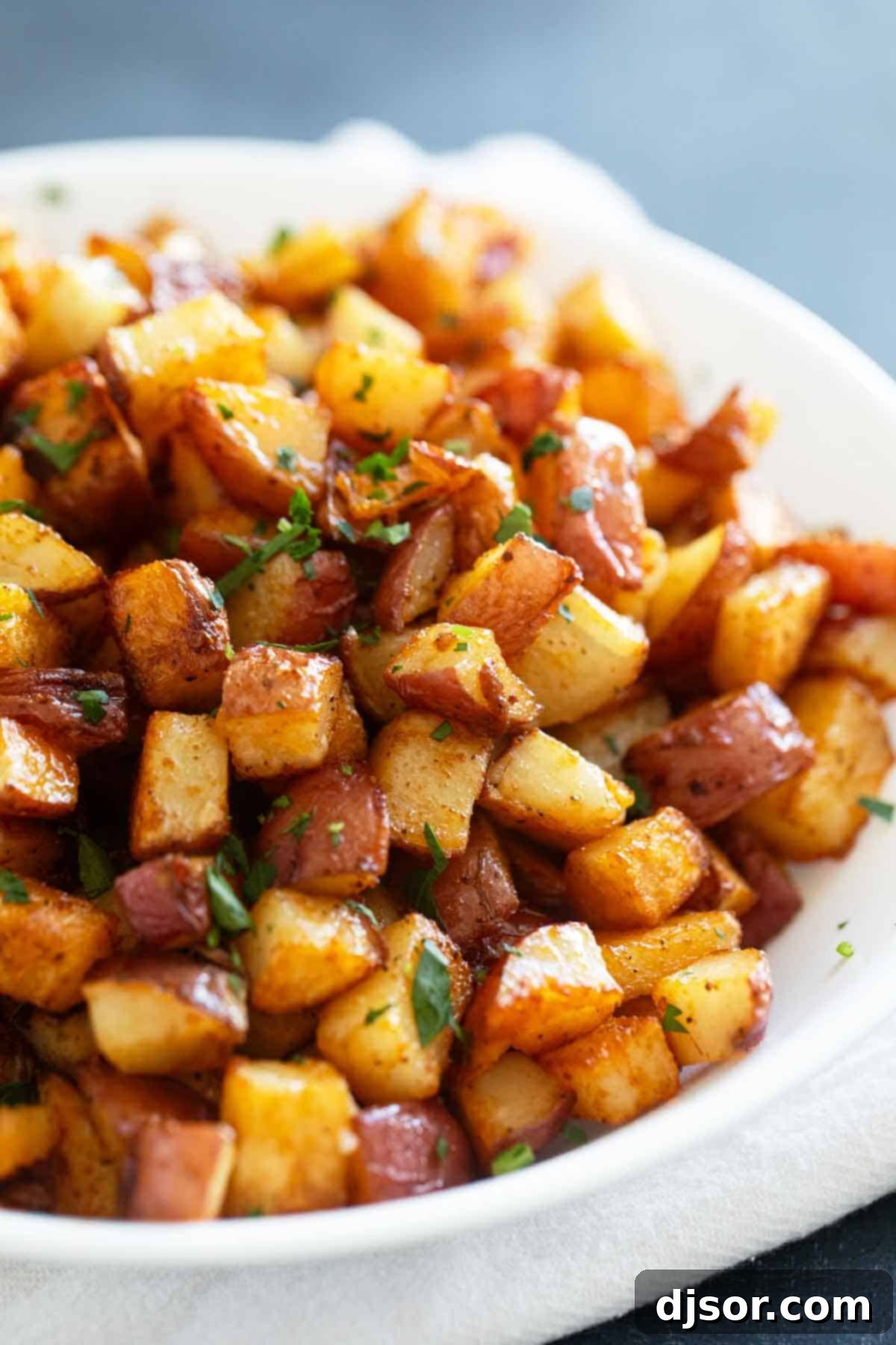 Freshly oven-roasted Breakfast Potatoes, golden and crispy, garnished generously with vibrant green fresh parsley on a baking sheet, ready to be served.