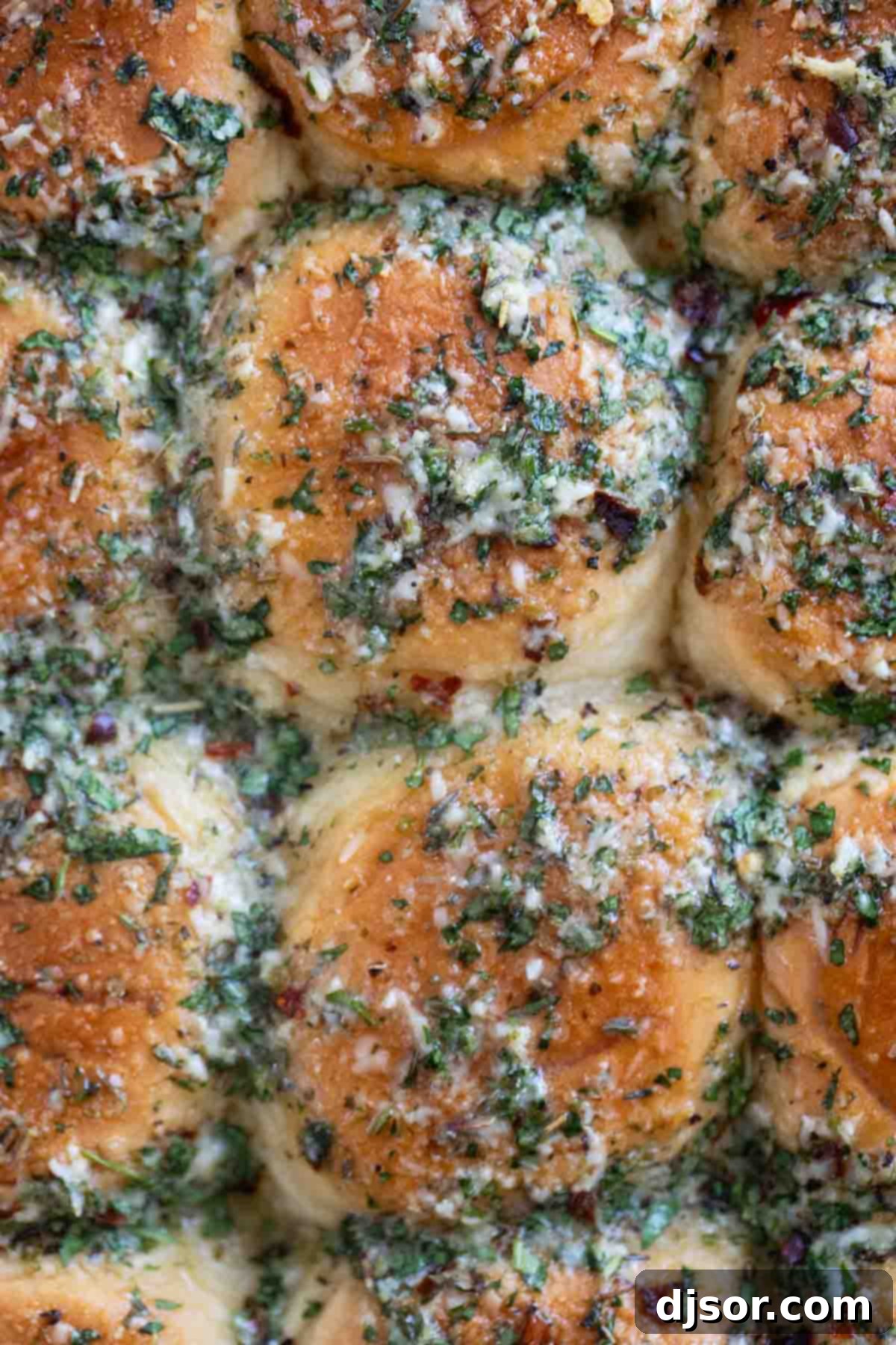 Pepperoni Pizza Poppers 7 Tops of pepperoni pizza sliders, showing herbs, butter, and red pepper flakes.